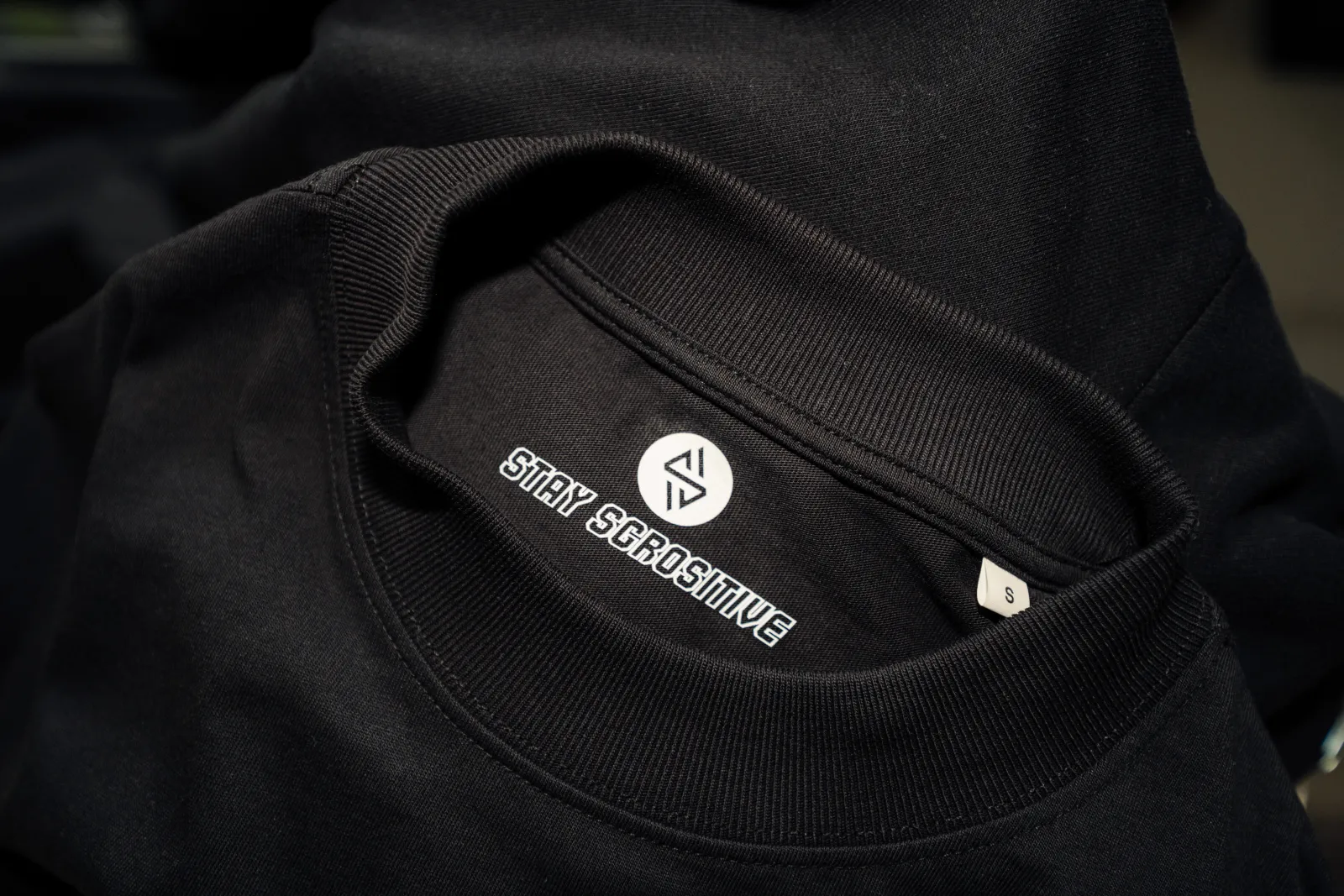 Nahaufnahme des Stay-SGROsitive-Nackenlabels im Kragen des Tees